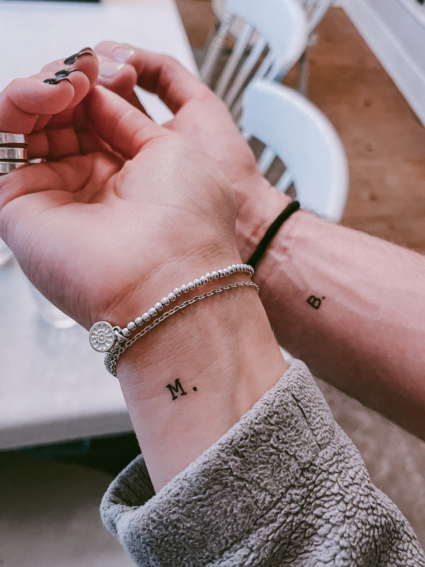 Close-up of a person's wrist with tattoos and bracelets, blurred background
