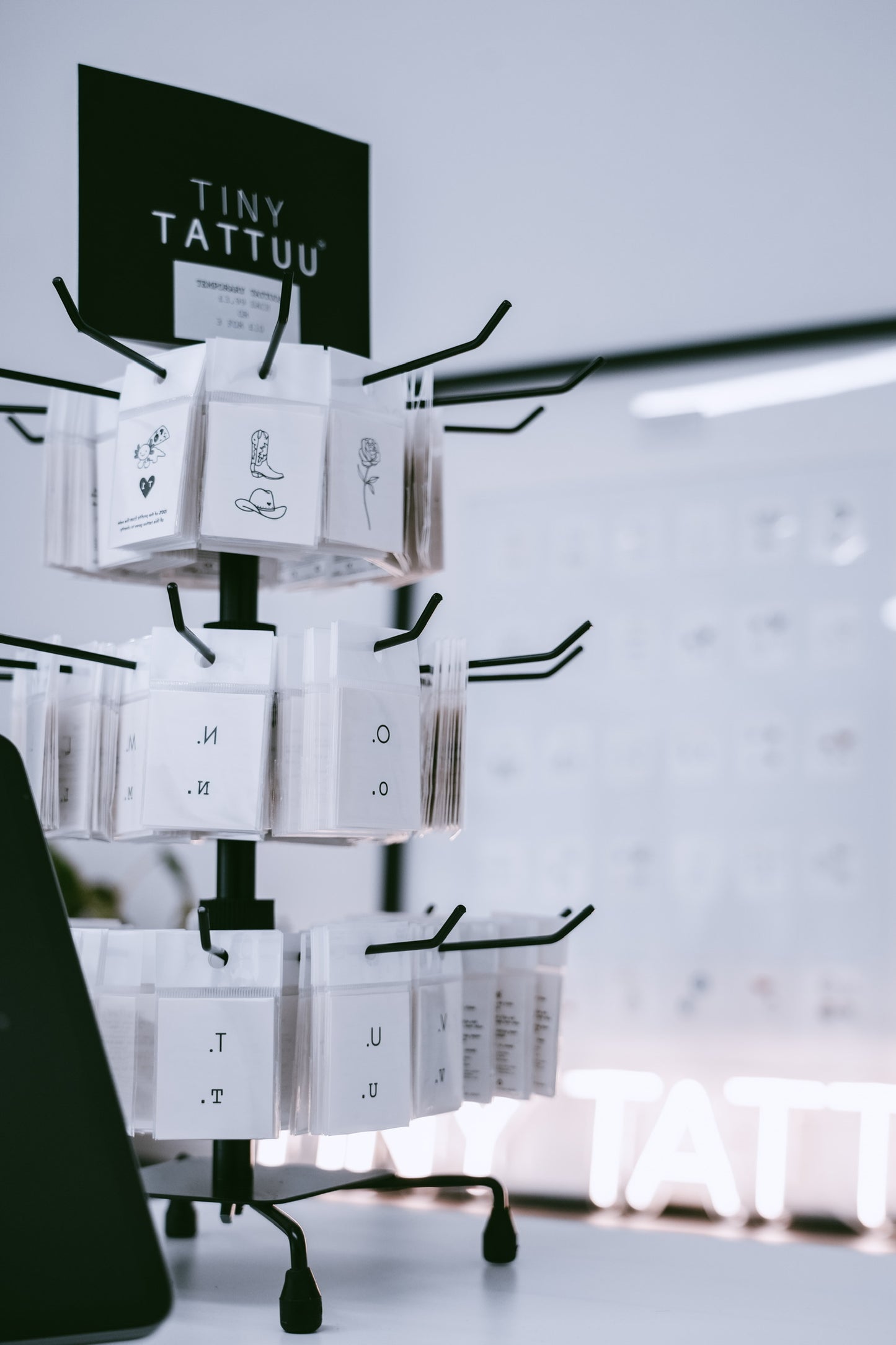 Display stand with 'Tiny Tattuu' product packaging against a light background