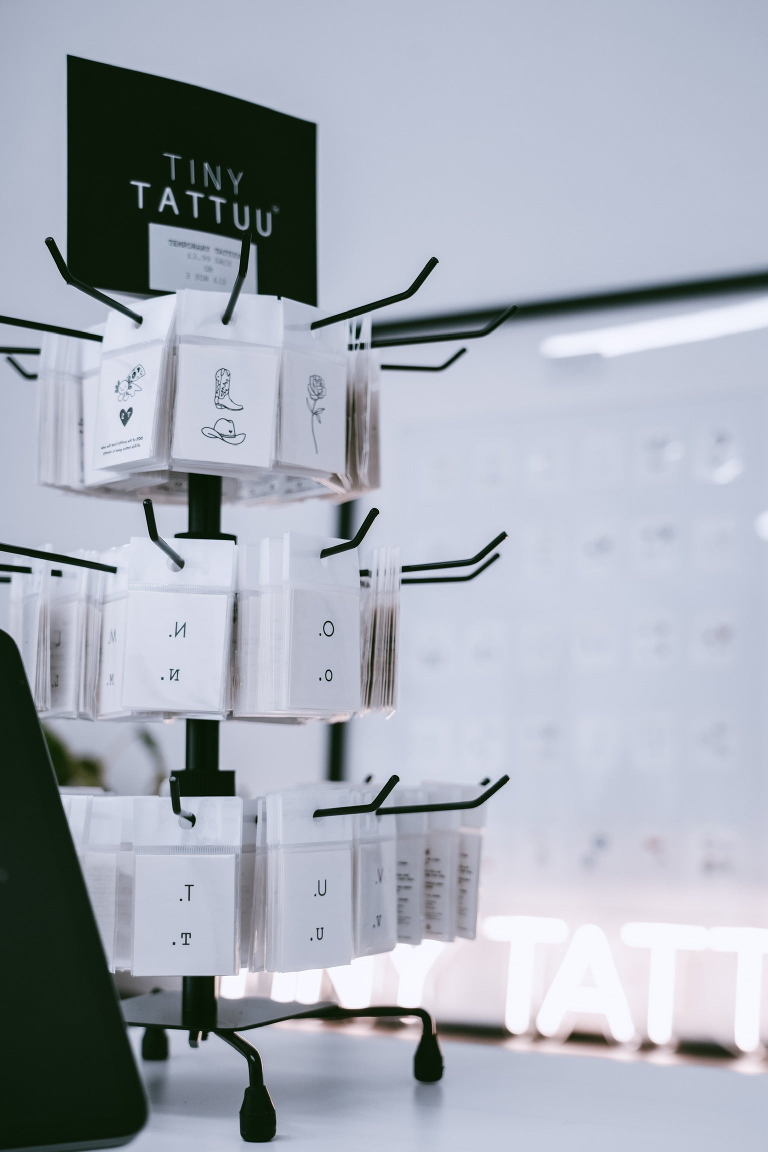 Display stand with 'Tiny Tattuu' product packaging against a light background