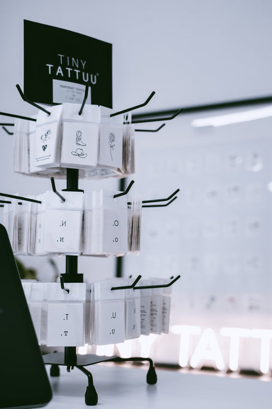 Display stand with 'Tiny Tattuu' product packaging against a light background